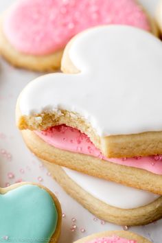 cookies with pink and white frosting in the shape of a heart on a table