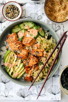 a bowl filled with shrimp and rice next to chopsticks on top of a table