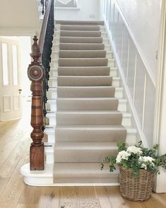 the stairs are lined with beige carpet and white railings, along with a basket full of flowers