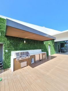 an outdoor kitchen and grill area on a deck with grass growing up the side of it