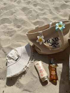 a hat, sunscreen and lotion are laying on the sand