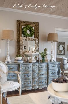 an antique dresser is decorated with wreaths and other decor in this elegant living room