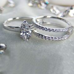 two wedding rings with diamond accents on a silver surface, surrounded by other jewelry pieces