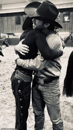 two men hugging each other while wearing cowboy hats