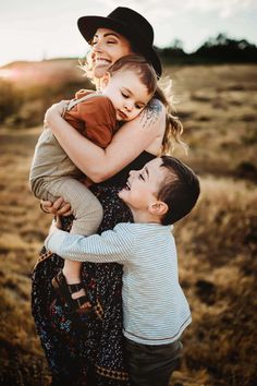 three children hugging each other in the middle of a field