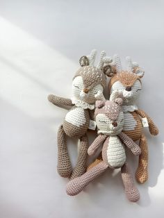 three crocheted stuffed animals sitting next to each other on a white table top