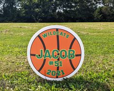 an orange and white sign with the words wildcats jacob on it in grass