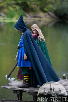 two people dressed in medieval costumes standing on a dock