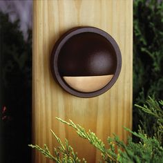 a close up of a light on a wooden object near some plants and trees in the background