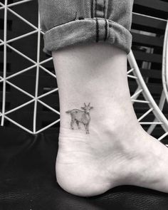 a small goat tattoo on the ankle, with an animal in the middle of it