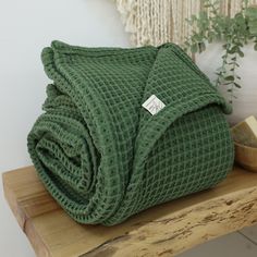 a green blanket sitting on top of a wooden table next to a potted plant