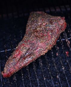 a steak is cooking on the grill with some seasoning sprinkled over it