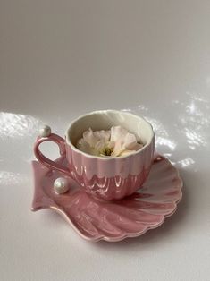 a pink teacup with flowers in it sitting on a saucer