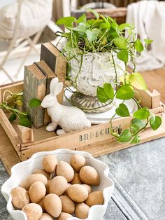 a bowl of potatoes sitting on top of a table next to a potted plant