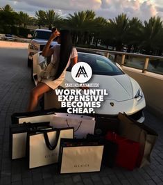 a woman sitting on top of a white car next to lots of boxes and bags