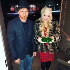 a man and woman dressed in costumes holding a plate with green food on it while standing next to each other