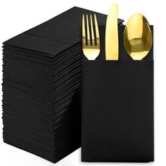 a stack of black napkins with gold forks and spoons on top of them