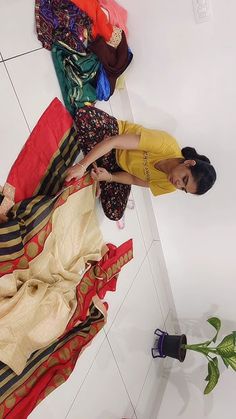 a woman standing next to a pile of clothes on top of a white tiled floor