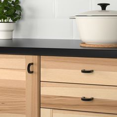 a potted plant sitting on top of a wooden cabinet next to a black counter