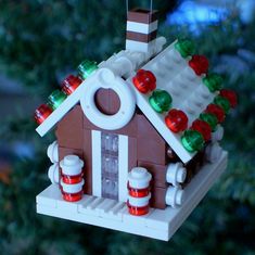 a birdhouse made out of legos with candy on the roof and lights hanging from it