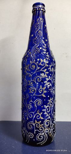 a blue vase with gold swirls on it sitting on top of a black table