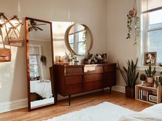 a bedroom with a dresser, mirror and plants