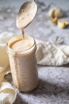 a spoon full of liquid being poured into a jar