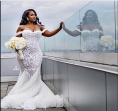 a woman in a white wedding dress standing on a balcony with her arms out to the side