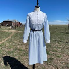 "^ 70s Light Blue & White Seer Sucker Fabric Collarless Long Sleeve Dress with White Contrast Cuff & Pleat Front Fabric Panel with Lace Edging Detail. This has White Buttons up the Top Half & Cuffs, Elastic Waist and and comes with navy fabric belt with gold circle adjustable buckle with gold tip. Women's Size: M/L (see measurements below) Vintage Size: 9 or 10 Content: Stripe Fabric 65% 35% Poly, Solid Fabric 50% Poly 50% Cotton Label: Avon Fashions ^ Please note specific garment me 1970s Long Sleeve Prairie Dress, Vintage Knee-length Fitted Prairie Dress, Vintage Fitted Knee-length Prairie Dress, Daywear Long Sleeve Retro Prairie Dress, Vintage Blue Long Sleeve Prairie Dress, Retro Prairie Dress For Daywear, Retro Long Sleeve Prairie Dress For Daywear, Retro Long Sleeve Prairie Dress For Summer, Retro Summer Prairie Dress With Long Sleeves