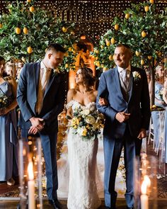 a bride and groom walking down the aisle at their wedding ceremony with orange trees in the background