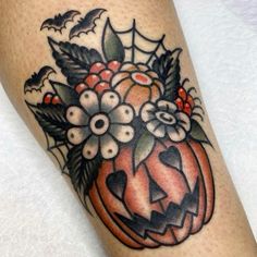 a close up of a person's leg with a pumpkin and flowers on it