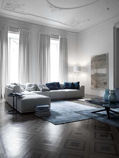 a living room filled with white furniture and blue pillows on top of it's couches