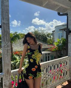 a woman is standing on a porch holding a handbag