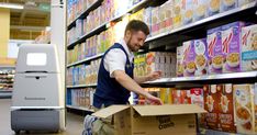 a man is picking out some food from a cardboard box in a grocery store aisle