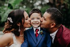 a young boy in a suit kissing his mother and father