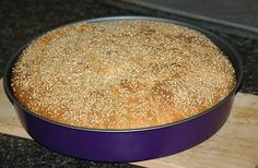 a blue pan filled with bread sitting on top of a wooden cutting board next to a black counter