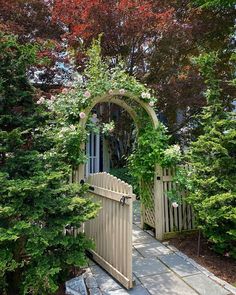 an arch in the middle of a garden with flowers growing over it's gate