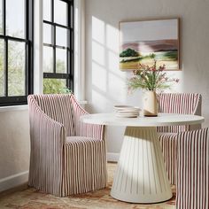 a dining room with striped chairs and a round table in front of a large window