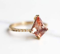 a ring with an orange stone and white diamonds on the side, sitting on a table