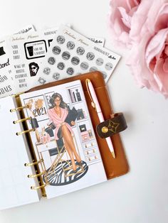 an open planner with stickers on it next to a pink carnation and pen