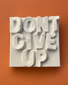 the words don't give up are made out of white foam on an orange background