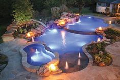 an outdoor swimming pool lit up at night with candles on the edge and lights in the water