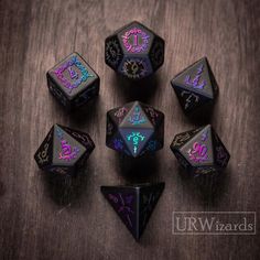 six black dice with purple and blue designs on the sides, sitting on a wooden table