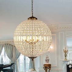 a chandelier hanging from the ceiling in a living room next to a piano