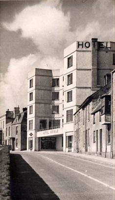 an old black and white photo of a street with buildings on both sides that have the word hotel written on it