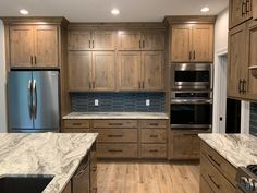 a large kitchen with wooden cabinets and marble counter tops, along with stainless steel appliances