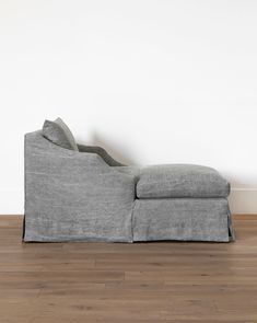 a gray couch sitting on top of a hard wood floor next to a white wall