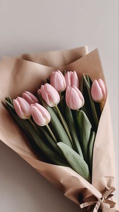 a bouquet of pink tulips wrapped in brown paper