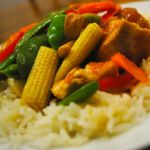 a white plate topped with rice and meat covered in veggies on top of it