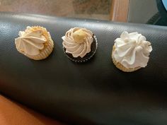 three cupcakes sitting on top of a black table